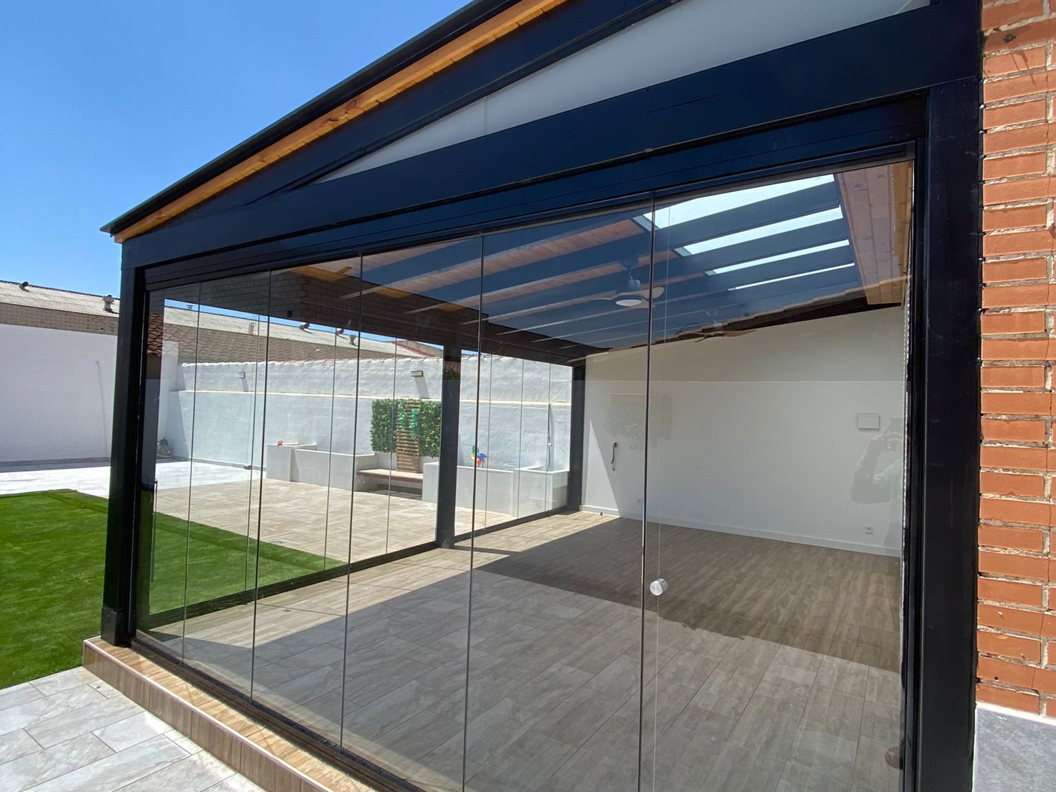 Porche con tragaluz y cortinas de cristal.