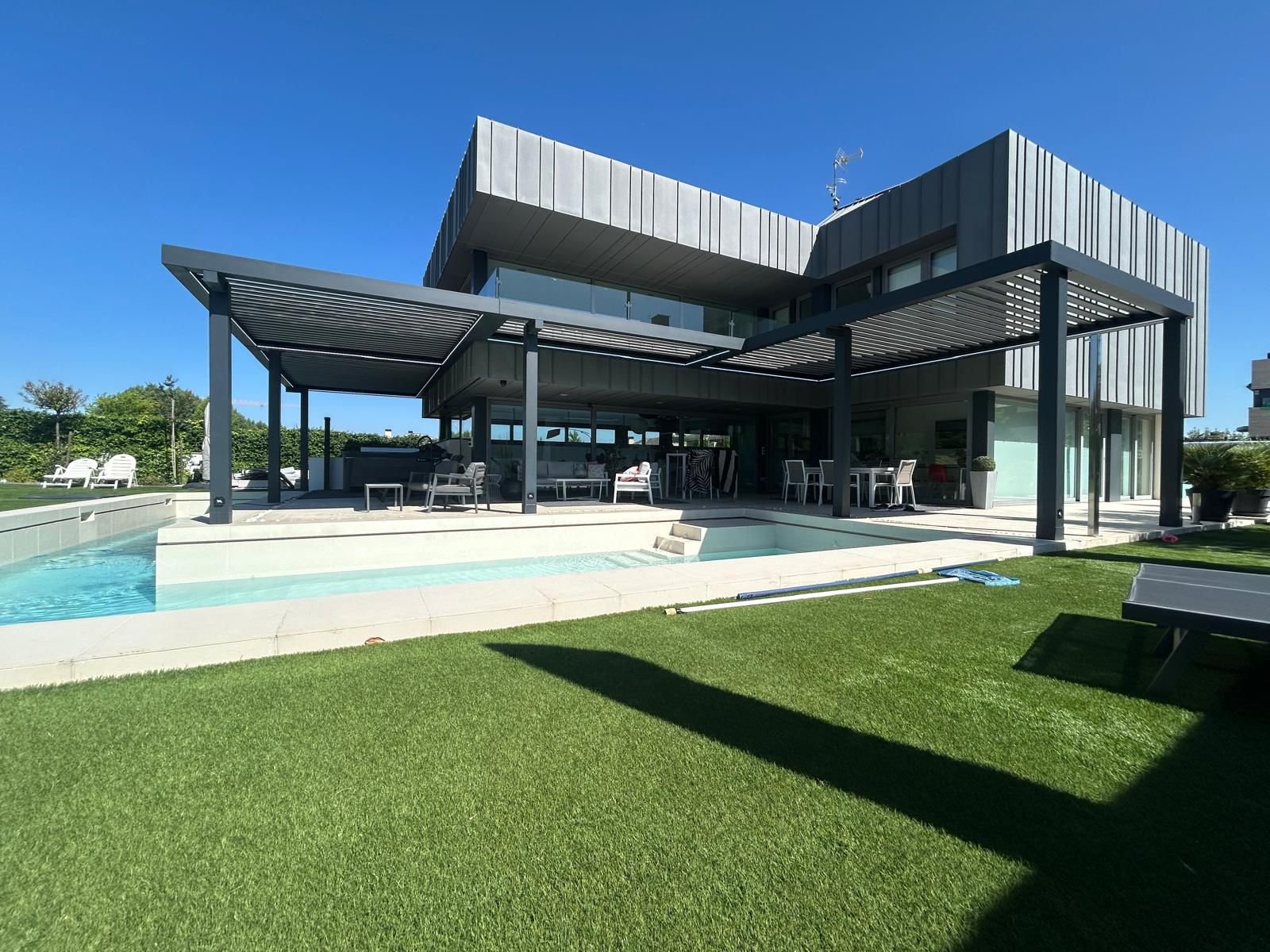 En la imagen se ve una casa de estilo futurista con una pergola bioclimatica