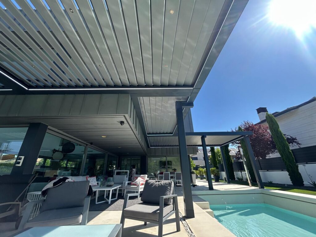 En la imagen se ve una pergola bioclimatica siguiendo el contorno de la vivienda