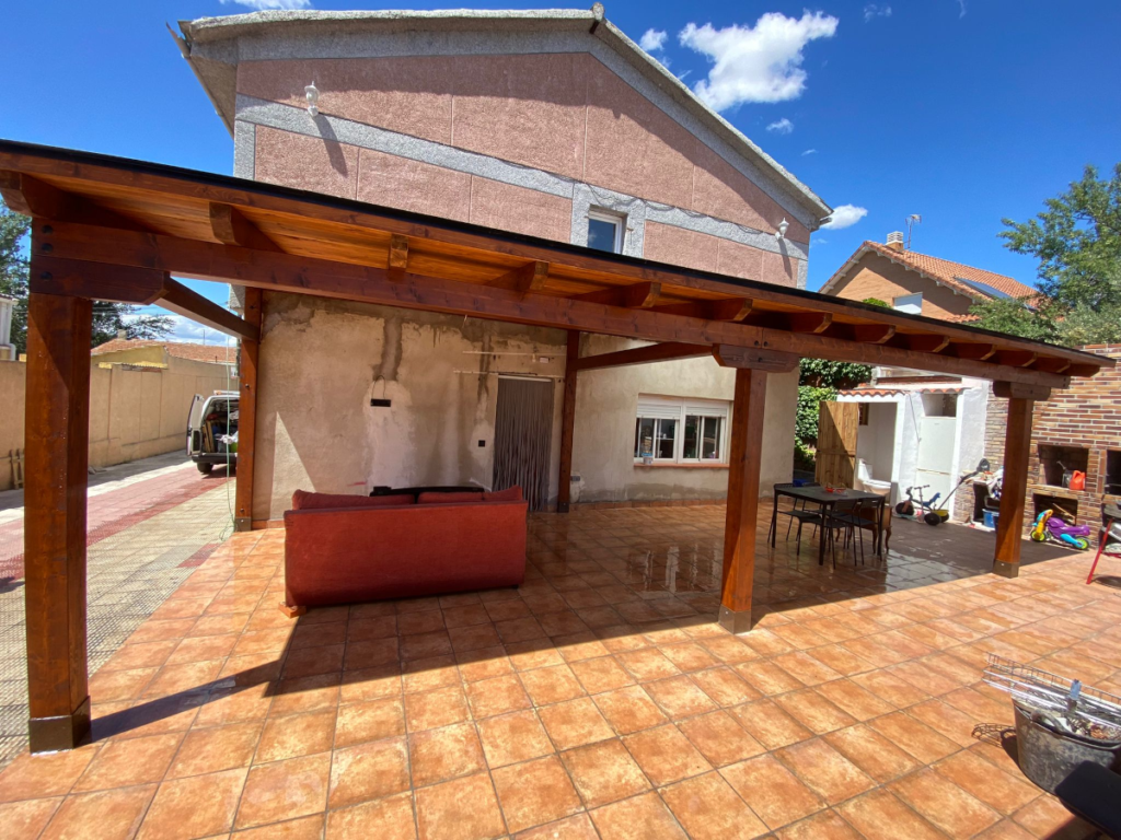 En la imagen se ve un porche rustico en el patio trasero de un chalet en proceso de reforma