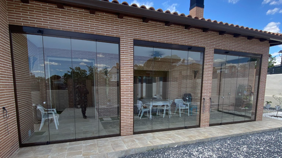 En la imagen se ve el porche de ladrillo despues de colocar la cortina de cristal
