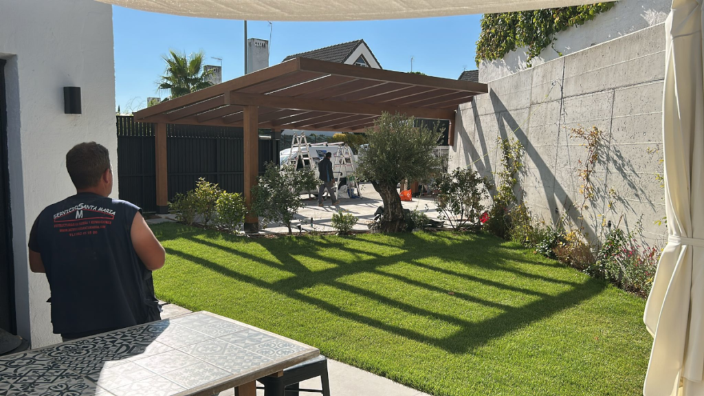 En la imagen se ve una pergola de madera en el paso de carruajes de un chalet terminada
