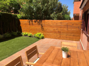 En la imagen se ve una valla de madera en un jardin con plantas