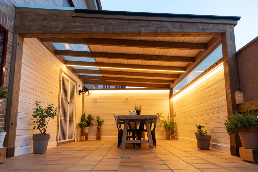 En la foto se ve un porche de madera con tragaluz acristalado en un patio