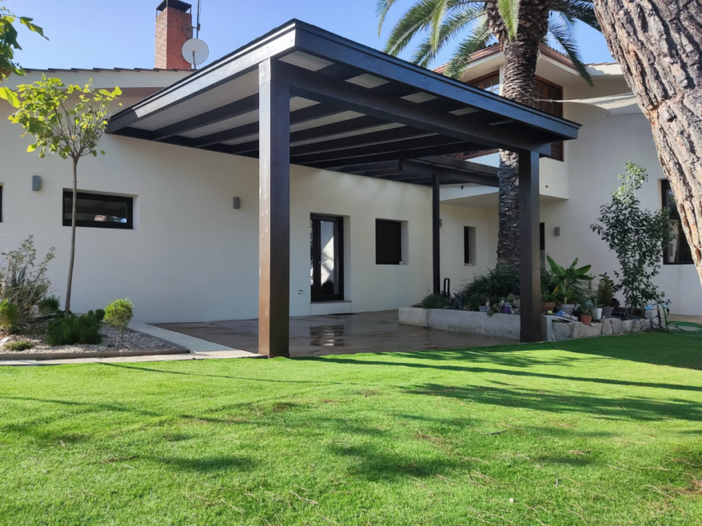 En la imagen se ve un porche de madera de lujo en el patio trasero de un chalet en la urbanizacion La Finca, en Madrid