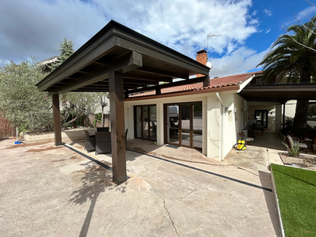 En la magen se ve el detalle lateral de un porche de madera de lujo en la urbanizacion la finca, en Madrid