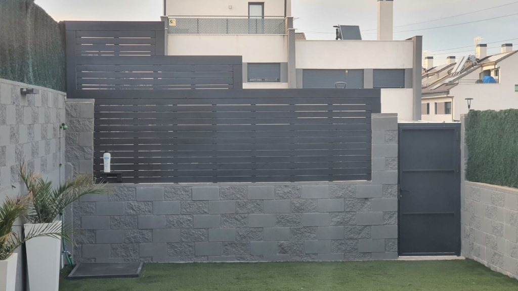 En la imagen se ve una valla de madera sobre un muro de bloques