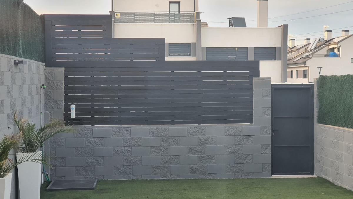 En la imagen se ve una valla de madera sobre un muro de bloques