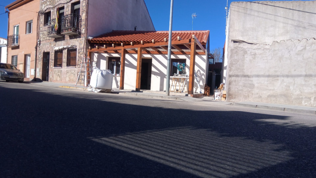 En la imagen se ve una pergola adosada a una casa en la calle
