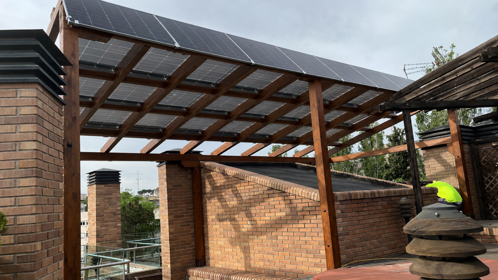 En la imagen se ve una pergola en una azotea con placas solares instaladas encima
