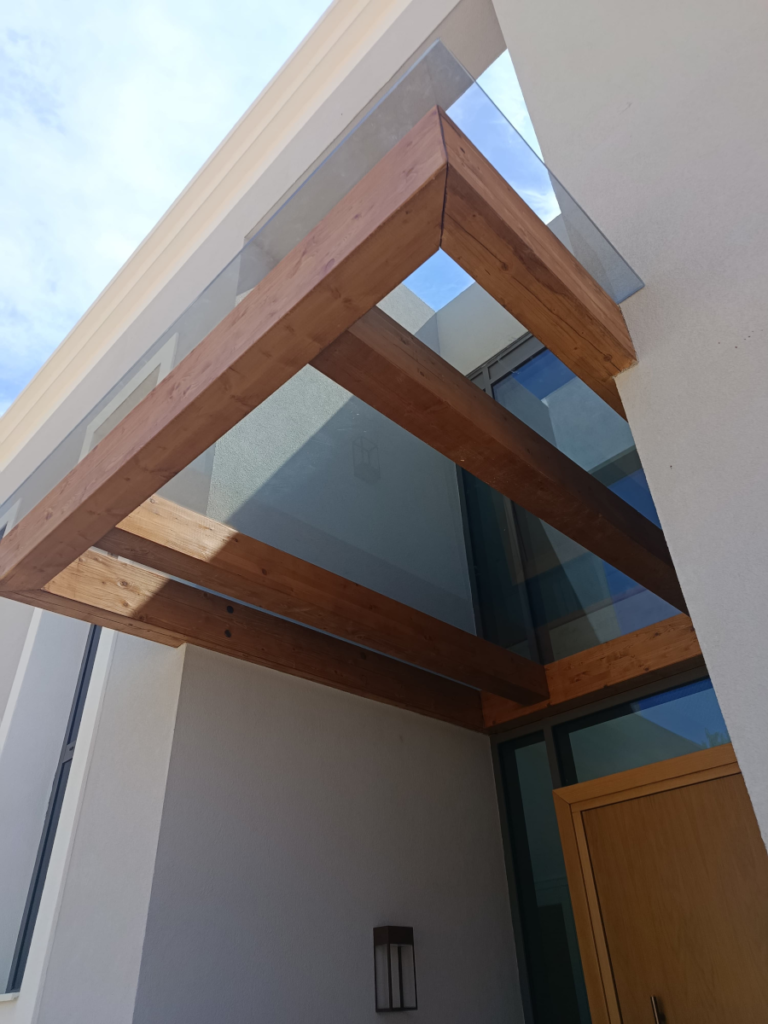 En la imagen se ve una marquesina de estilo moderno cubierta con un cristal laminado
